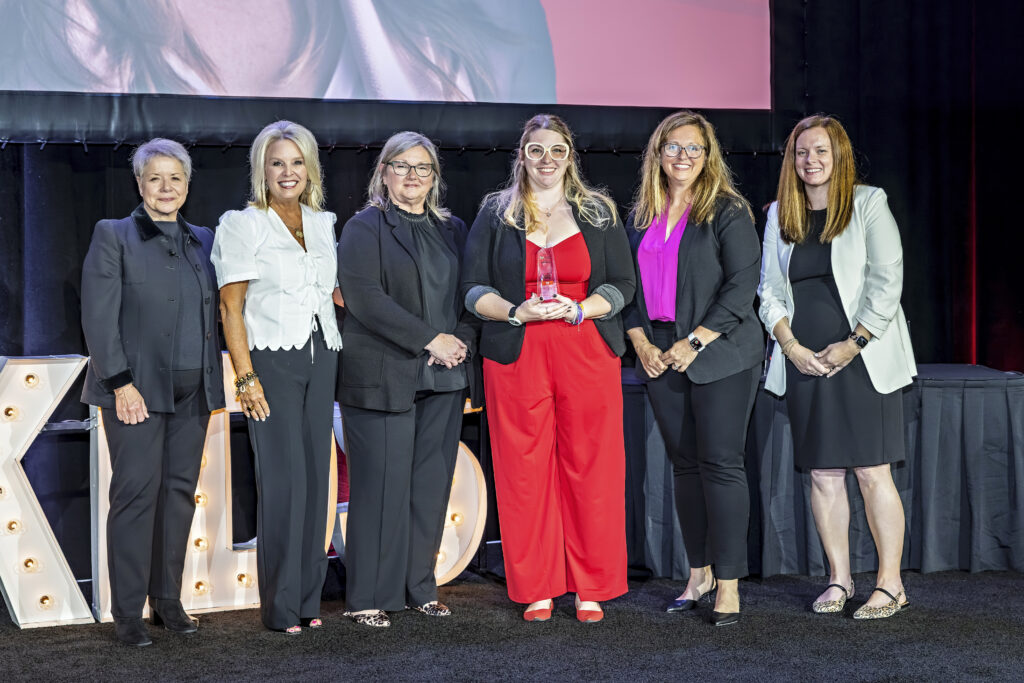 Molly accepting her award onstage, smiling alongside Foundation Staff.