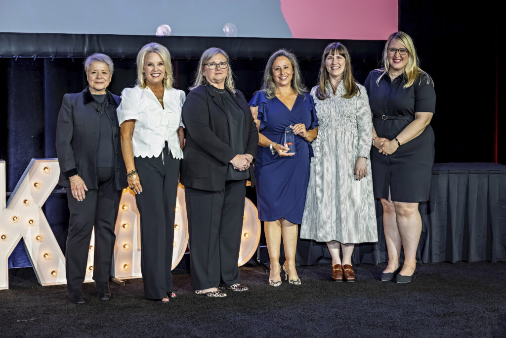 Sandra accepting her award onstage, smiling alongside Foundation Staff.