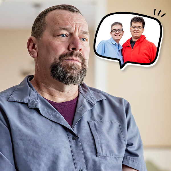 A middle-aged man with a beard looks thoughtful, with a cartoon speech bubble next to his head showing his two sons.