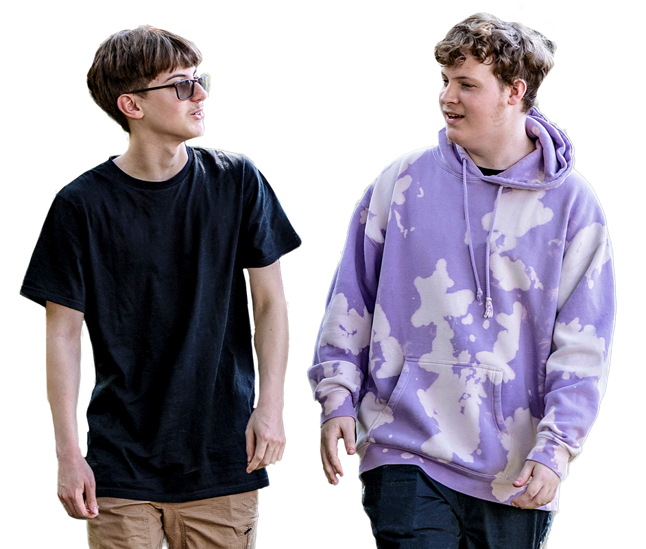 Two young men walking and talking. One wears sunglasses, a black t-shirt, and tan shorts; the other wears a purple and white tie-dye hoodie and dark pants. Both appear relaxed and engaged in conversation.