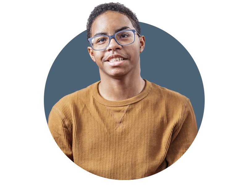 A person wearing blue glasses and a brown textured sweater is smiling slightly, looking at the camera. The background is a solid blue circle.